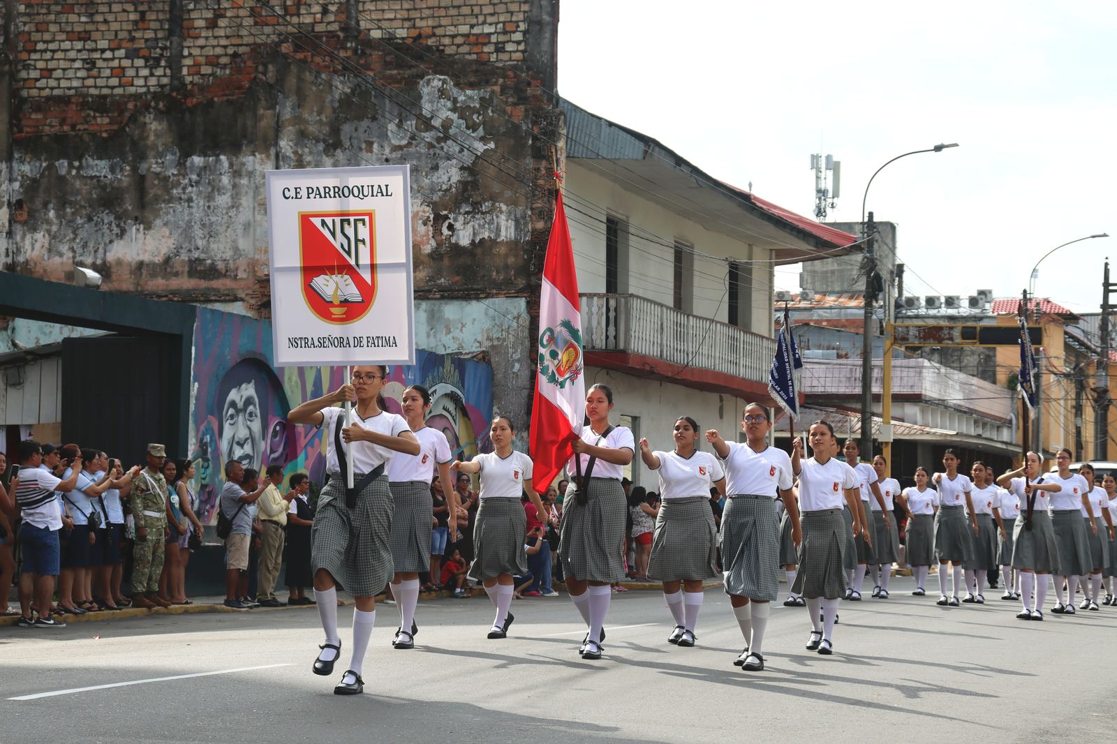 Estudiantes desfilando con el estandarte del colegio